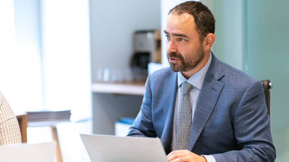 Financial strategies for EB-5 success featuring three financial experts from CanAm Enterprises, with a modern cityscape background.